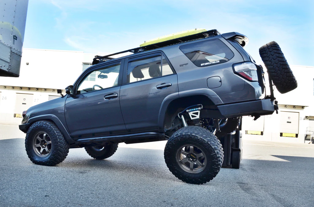 Toyota 4Runner gris con neumáticos todoterreno y la rueda trasera sobre una rampa.